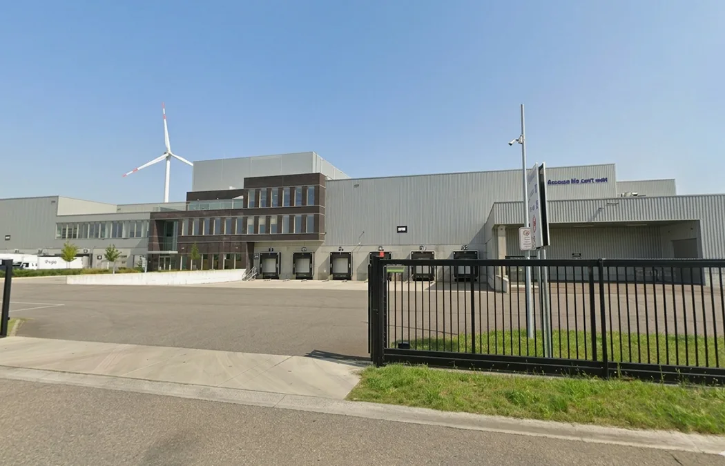 Een bedrijfsterrein achter een gesloten hek, met een verbodsbord aan de ingang.